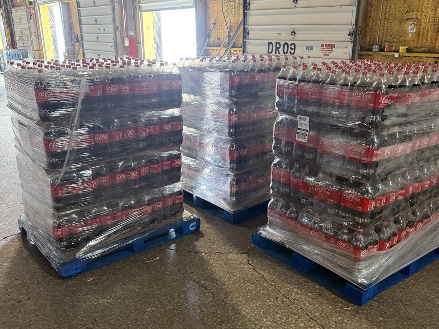 Three wrapped pallets staged on the floor in front of numbered dock doors