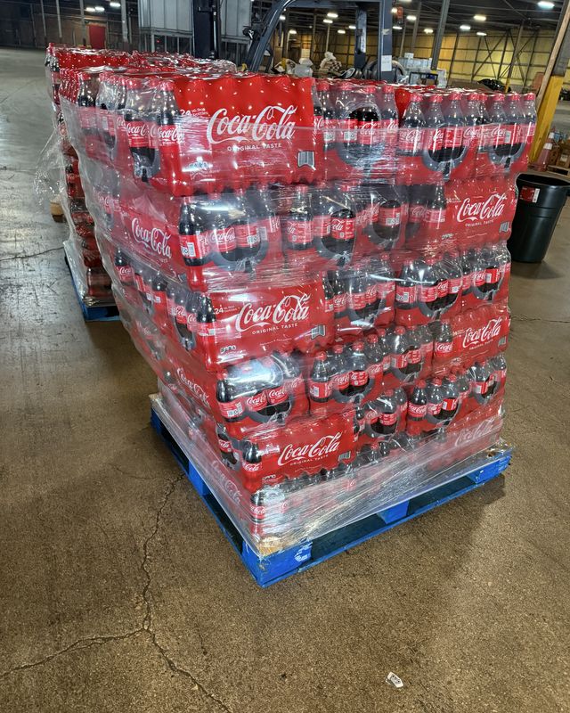 A wrapped pallet of cases ready for loading, warehouse racking behind